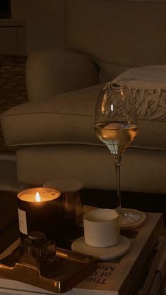 a glass of wine sitting on top of a table next to a candle