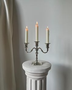 three candles are lit on top of a pedestal