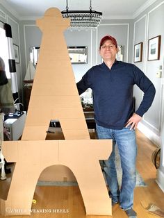 a man standing next to a cardboard model of the eiffel tower