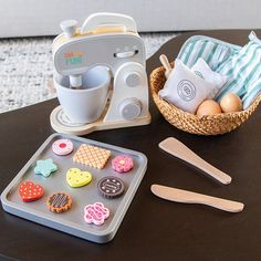 a toy kitchen set on a table next to a basket with food and utensils