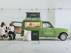 a green truck parked in a garage next to a wooden table and chair with lights on it