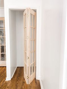 an open door in the corner of a room with wood flooring and white walls