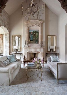 a living room filled with furniture and a chandelier hanging from the ceiling next to a fire place