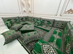 a green couch covered in intricately designed pillows