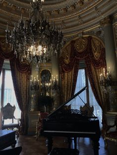 a grand piano sits in the middle of a room with chandeliers and curtains