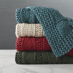 a pile of folded blankets sitting on top of a white marble counter next to a gray wall