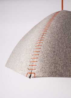 a gray and orange lamp shade with stitching on the side, hanging from an orange cord