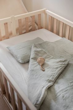 an unmade crib with a sea shell on the pillow and some linens