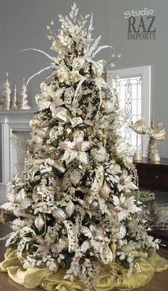 a white christmas tree in a living room with gold trimmings and ornaments on it