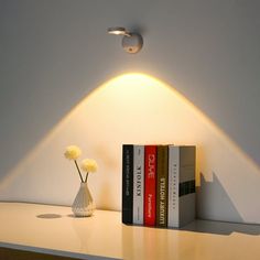 two books are sitting on a shelf next to a vase with flowers and a lamp