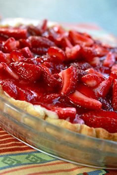 a close up of a pie with strawberries in it on a tableclothed cloth