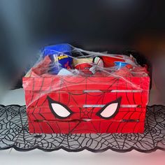 a red box with spiderman's face on it sitting on a lace doily