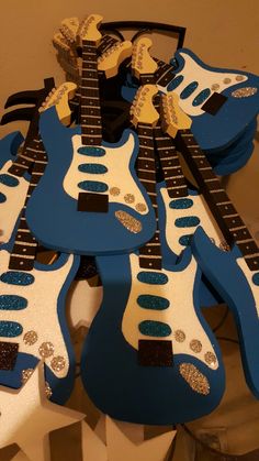 blue and white guitar shaped cookies are arranged in the shape of guitars with gold glitters on them