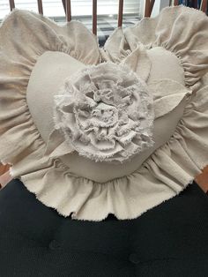 a white hat with ruffles and a flower on it's side sitting on top of a chair