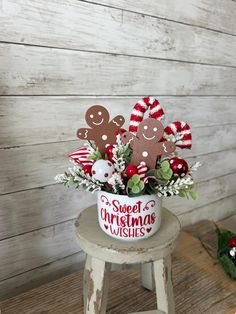 a small pot filled with christmas decorations on top of a wooden stool next to a wall