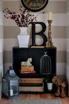 a shelf with books, vases and a clock on the wall above it in a room