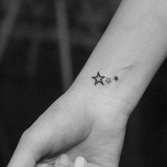 a small star tattoo on the left inner wrist is shown in this black and white photo