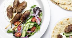 two plates with meat skewers, salad and pita bread