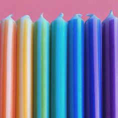 multicolored candles lined up against a pink background