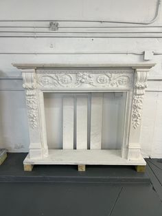 a white marble fireplace surround with carved designs