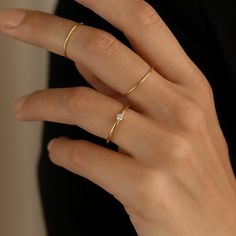 a woman's hand wearing a gold ring with a diamond on the middle finger