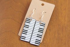 a pair of black and white piano keys dangle earrings on a card board background