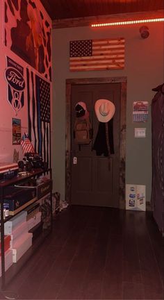 a room with an american flag painted on the wall and cowboy hats hanging from the ceiling