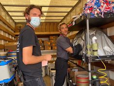 two men wearing masks in a storage area