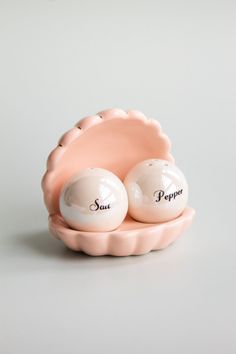 two salt and pepper shakers sitting in a shell shaped dish on a gray surface