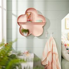 there is a pink cloud shaped shelf on the wall next to a potted plant