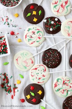 several decorated cookies on a white tablecloth with sprinkles and candies