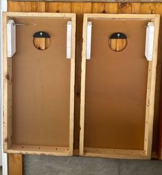 two wooden boxes with tags on them sitting next to each other in front of a wall