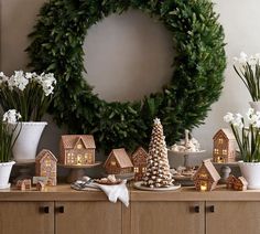 a table topped with lots of christmas decorations next to a wreath and potted plants