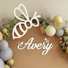 there is a sign that says avery on the wall next to some flowers and eggs