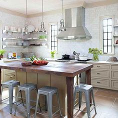 a kitchen island with stools in front of it and open shelves on the wall