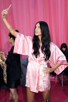 a woman is taking a selfie with her cell phone in front of pink curtains