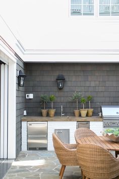 an outdoor kitchen with grill, table and chairs