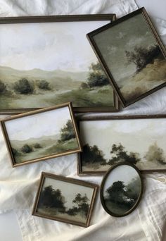 four framed paintings on a white sheet and one has a small painting in the middle