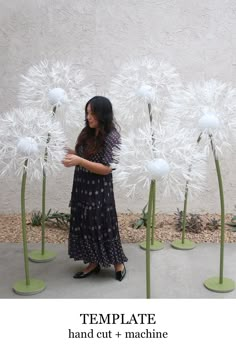 a woman standing in front of tall white flowers