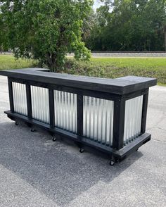 a large black box sitting on top of a cement road next to a tree and grass covered field