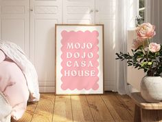 a pink poster with the words mojo dojo casa house next to a bed