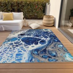 a blue and white area rug sitting on top of a wooden floor next to a couch