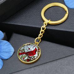 a gold keychain with a cardinal stained glass design on the front and back