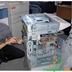 a man sitting on the floor next to an old computer tower with wires and other equipment