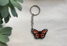 a keychain with a butterfly on it is sitting next to a potted plant