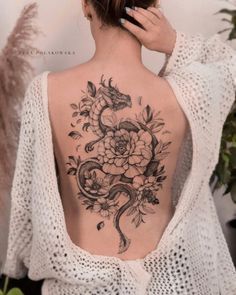 a woman's back tattoo with flowers and a snake