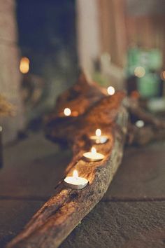 several lit candles are placed on a piece of wood