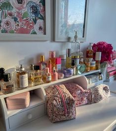 an assortment of perfumes and personal care products on a white shelf in a bathroom