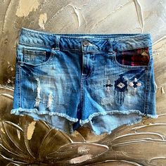 Embrace Bohemian Style With These Distressed Stretch Denim Shorts. The Blue Shorts Feature A Medium Wash And A Cut-Off Style, Perfect For Pairing With Your Favorite Boho Top. The Shorts Are Made Of High-Quality Denim Fabric, Ensuring Durability And Comfort. The Stretch Feature Of The Fabric Provides A Flattering Fit For All Body Types. These Shorts Are Perfect For Any Casual Occasion And Can Be Dressed Up Or Down Depending On The Occasion. Add These Shorts To Your Wardrobe Today And Step Out In Bohemian Denim Bottoms With Frayed Hem, Bohemian Dark Wash Jeans For Summer, Summer Bohemian Dark Wash Jeans, Bohemian Summer Jeans With Frayed Hem, Bohemian Jeans With Frayed Hem In Denim Blue, Casual Medium Wash Bottoms For Festival, Bohemian Light Wash Denim Bottoms, Distressed Blue Bottoms For Festival, Blue Distressed Bottoms For Festival