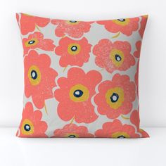 an orange and yellow flowered pillow on a white surface with a blue eye in the center